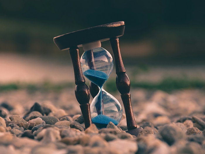 Hourglass sitting on a rocky beach