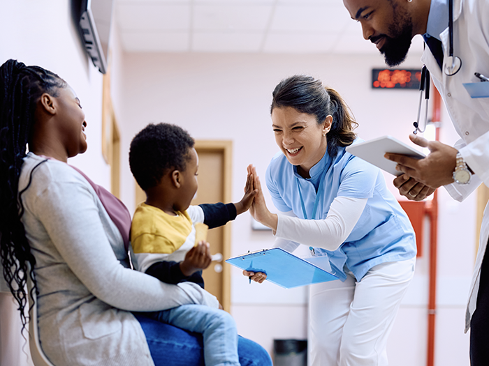 A young patient gives a high-five to a clinician.