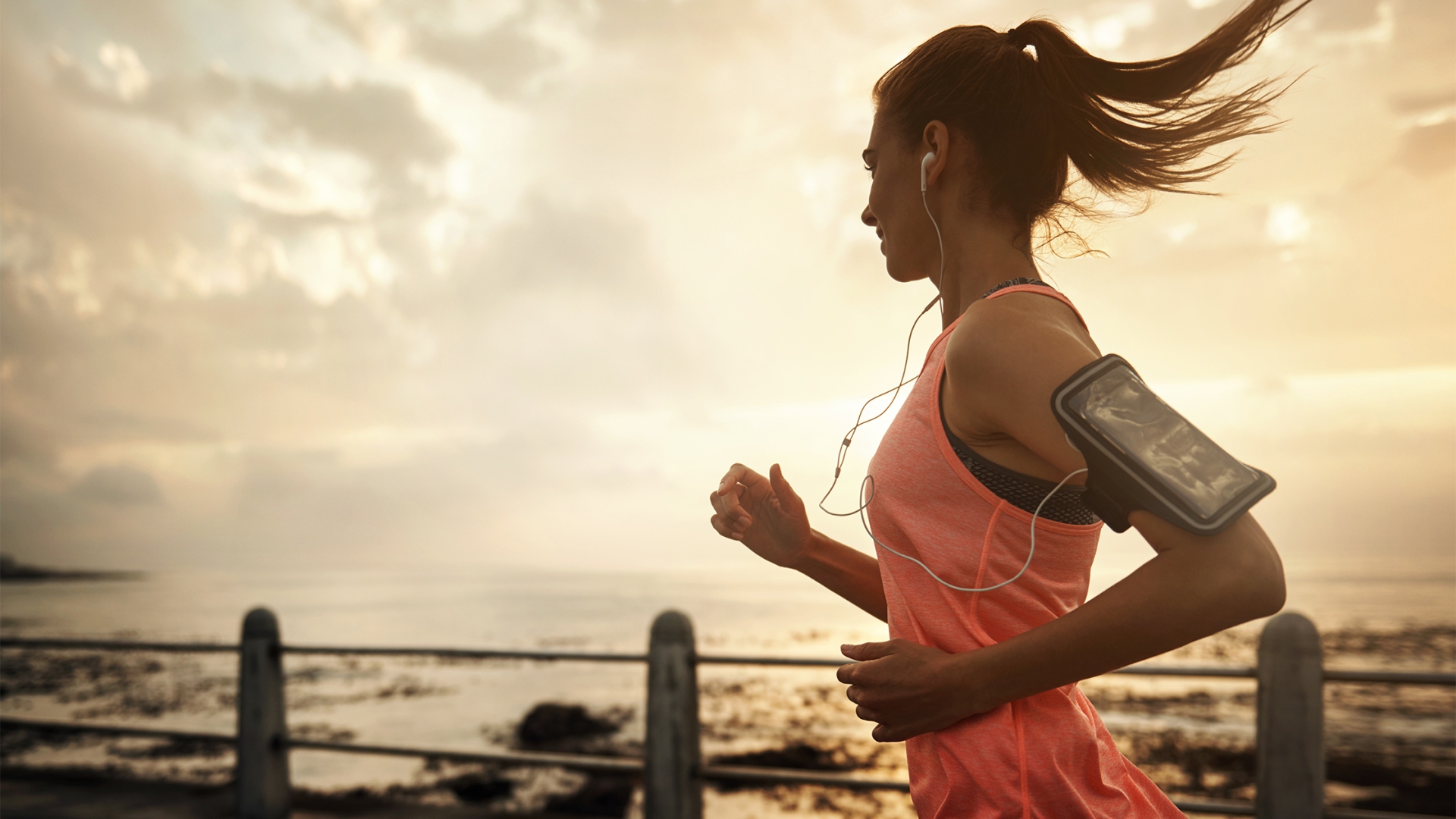 Shot of a young woman running on the promenade at sunset.