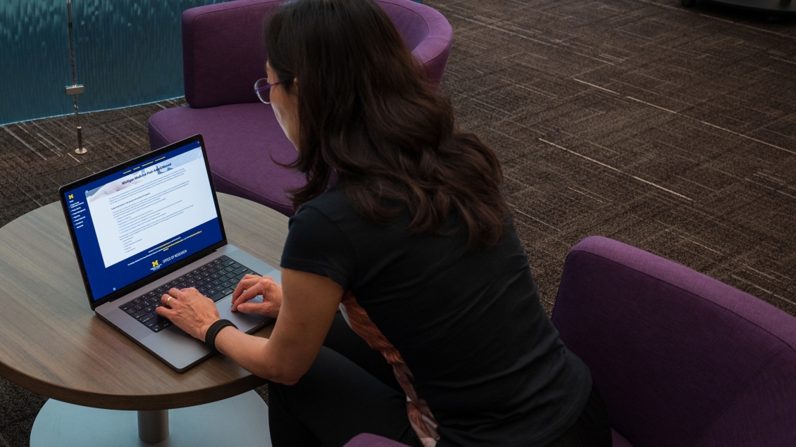 woman working on computer with Post Award Manual on the screen