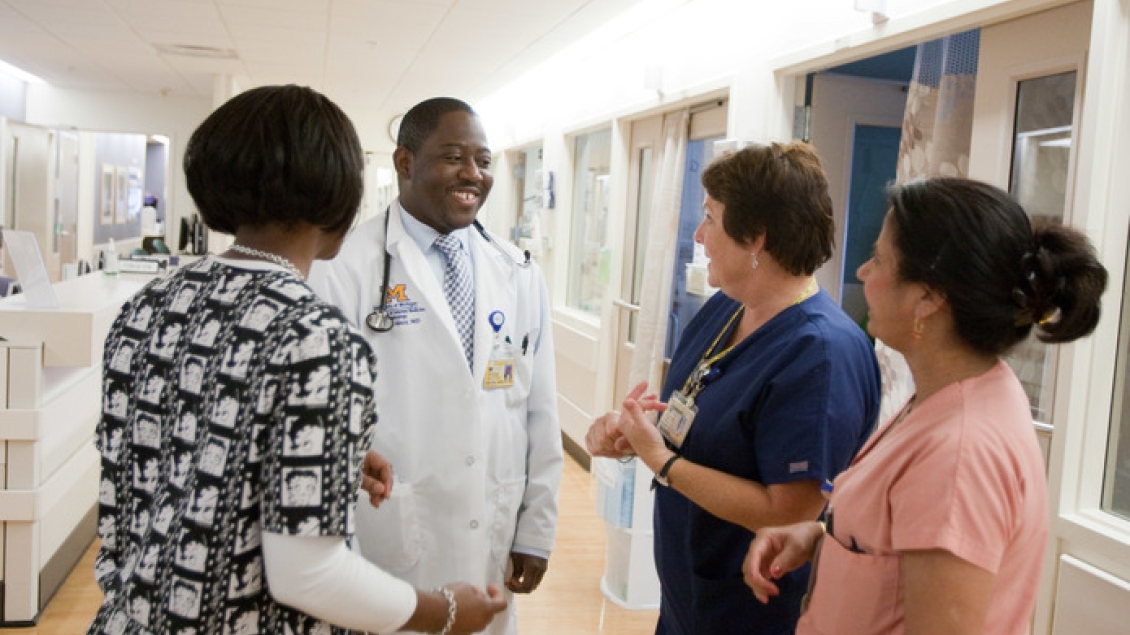 Doctor and clinical staff talking to each other in hallway.