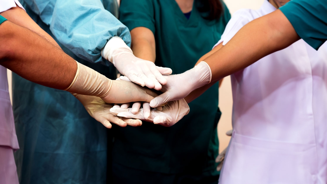 Five gloved hands of a medical team together in a circle