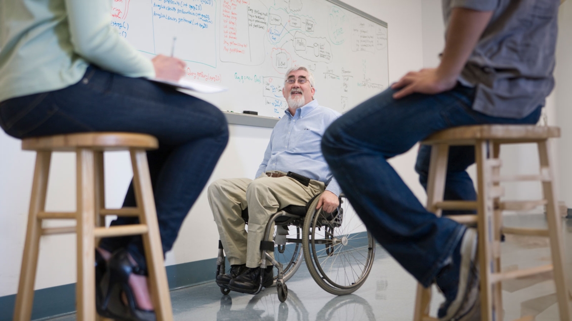 Professor in wheelchair facing class from whiteboard