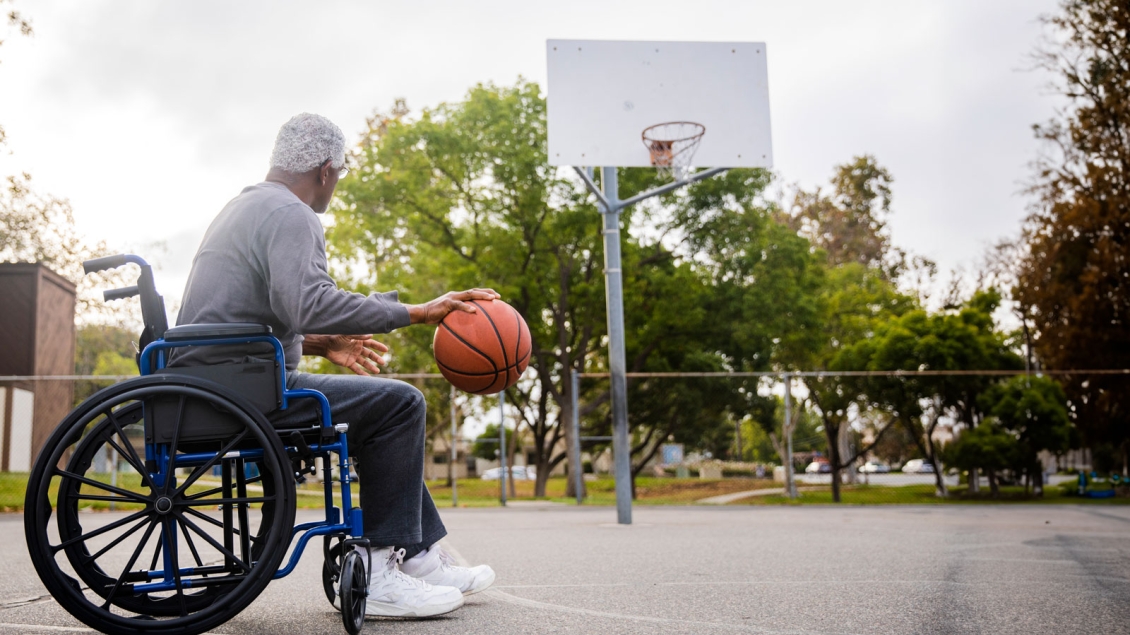 Senior in wheelchair at an outdoor basketball court