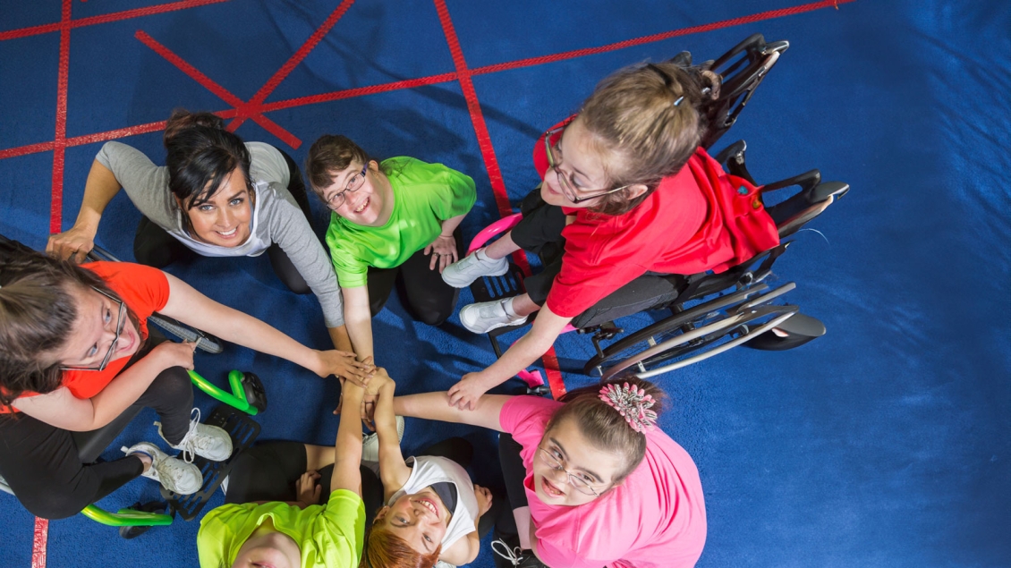 Gym students place hands in Center with Teacher